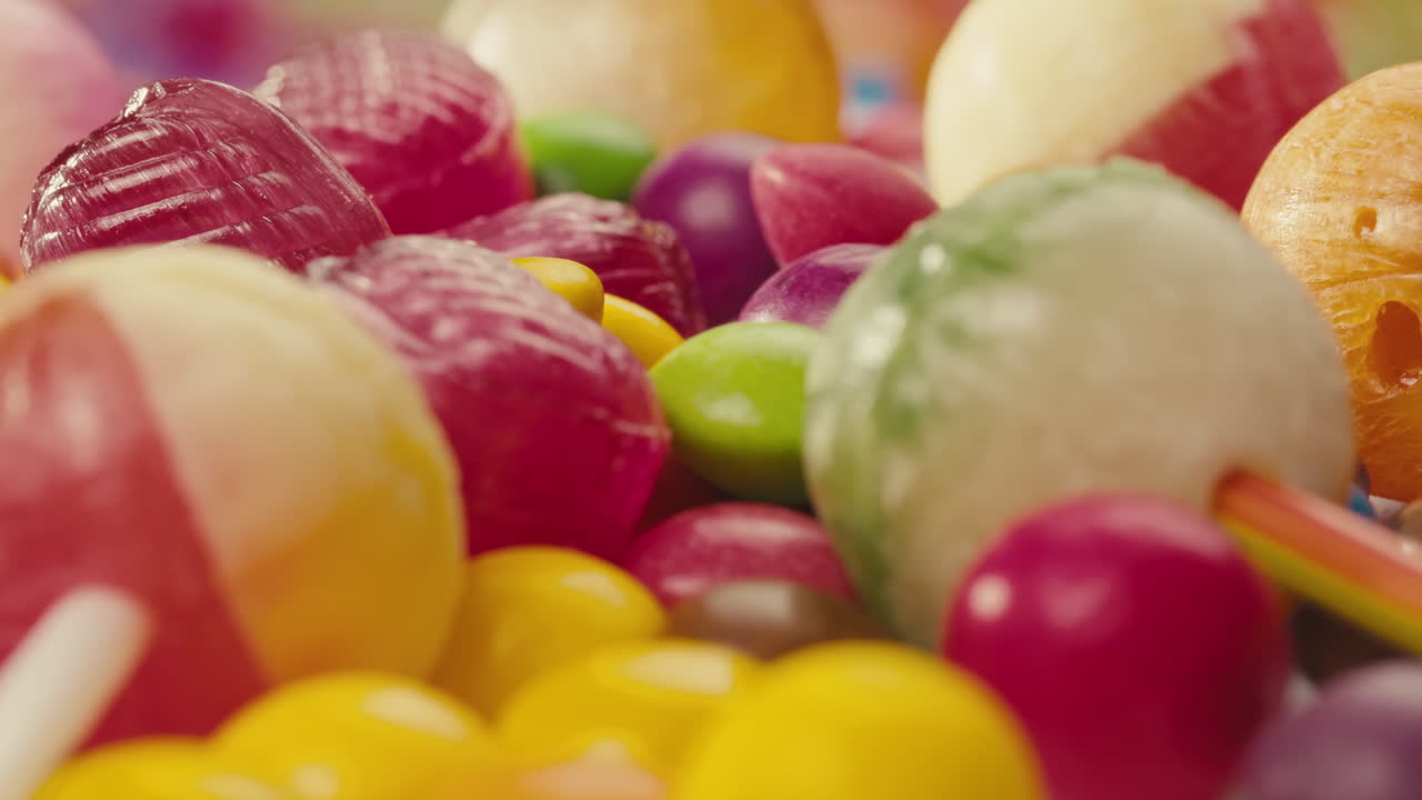 Colorful dragee candies, lollipops, bonbons on white background, move in circle, side view close-up. Summer bright texture studio shot for store, supermarket. Mix of children's sweets made of sugar.
