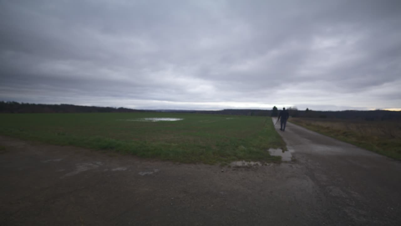 현대의 검은 검사 전사는 회색 하늘 아래 야외에서 대결 상대를 기다리고 있습니다 - 유럽, 4k - 근육, 협박, 그림자, 형상, 흐릿, 어두운 옷, 강력한, 흐릿한, 기, 멈추기, 검색