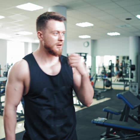 muscular man prouds of his strong body at the mirror in sports club. athletic male looking at mirror reflection in gym and posing, showing his muscles.