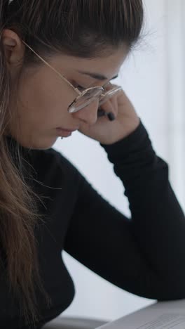 a woman with glasses studying or working intently