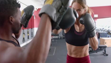 Una-Joven-Caucásica-En-Forma-Y-Un-Hombre-Afroamericano-Participan-En-Entrenamiento-De-Boxeo-En-El-Gimnasio