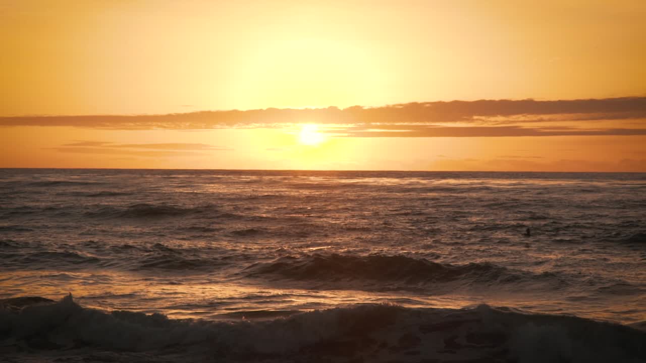 Birds flying over ocean waves during orange sky sunset in slow motion