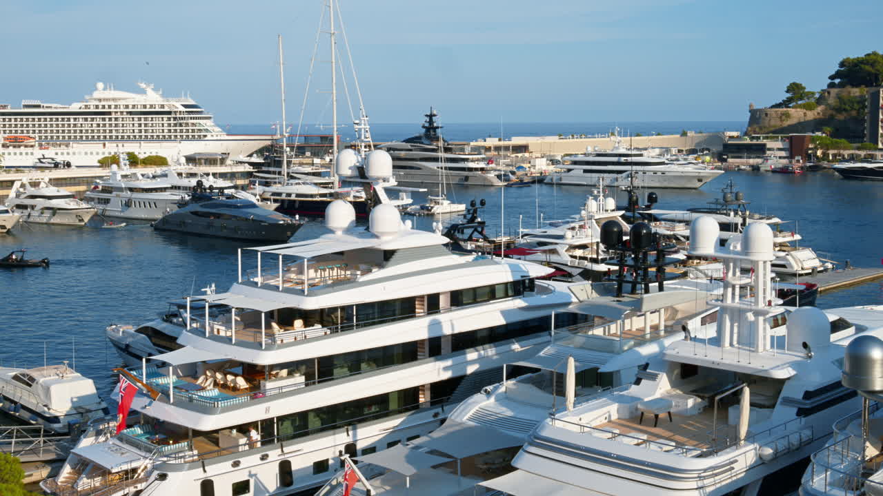 View of white boats docked in the Monaco Marina with the skyline of the city on the background