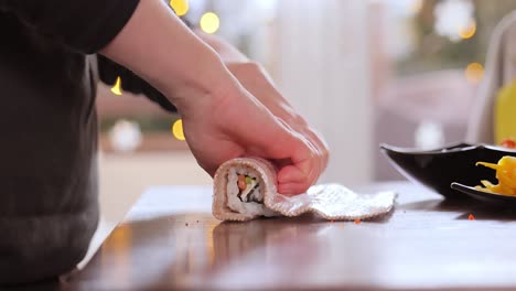 hacer sushi en la cocina de casa. manos de mujer enrollando sushi casero.