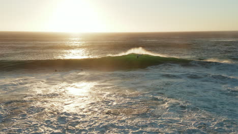 a body boarder catching a big wave with sunset while camera is tilting down in lladudno, cape town, south africa