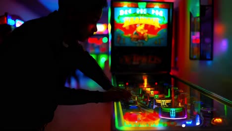 person playing pinball in a night arcade