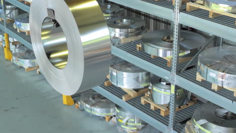 industrial shipping and manufacturing concept, carrying a large aluminum steel copper roll or metal coil being lifted by crane in warehouse environment