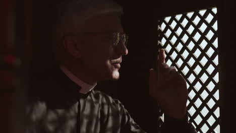 senior pastor sitting in confessional and listening confession
