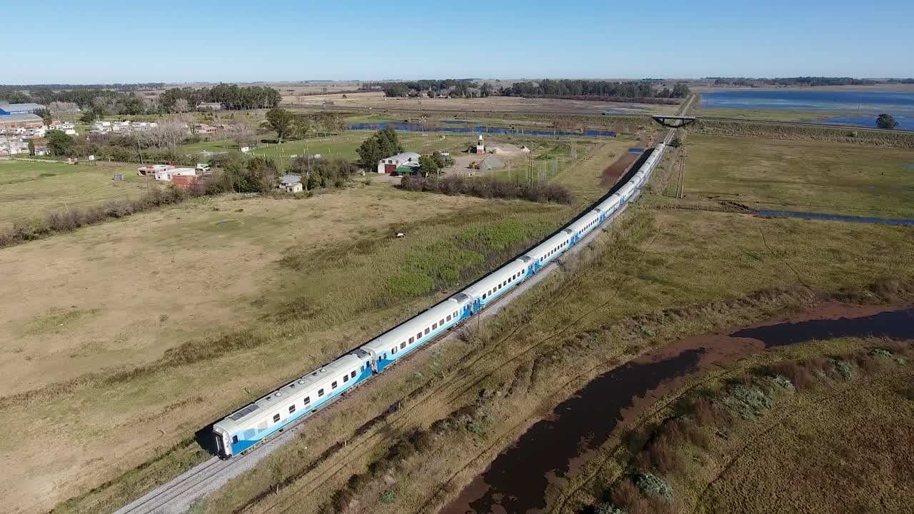 largo tren de pasajeros que viaja a través del campo, coches azules y blancos, cerca de buenos aires