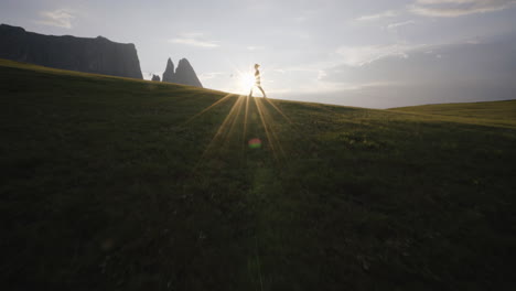 girl walking through the sun on the horizon on seisser alm in italy