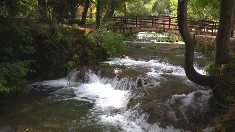 A-bridge-spanning-over-a-series-of-waterfalls-along-a-stream-in-Krka-National-Park-in-Croatia-at-¼-speed