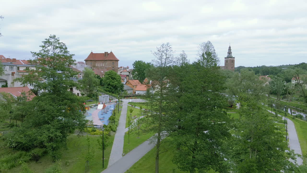 Descending aerial shot of blooming park with green trees and footpath in Poland