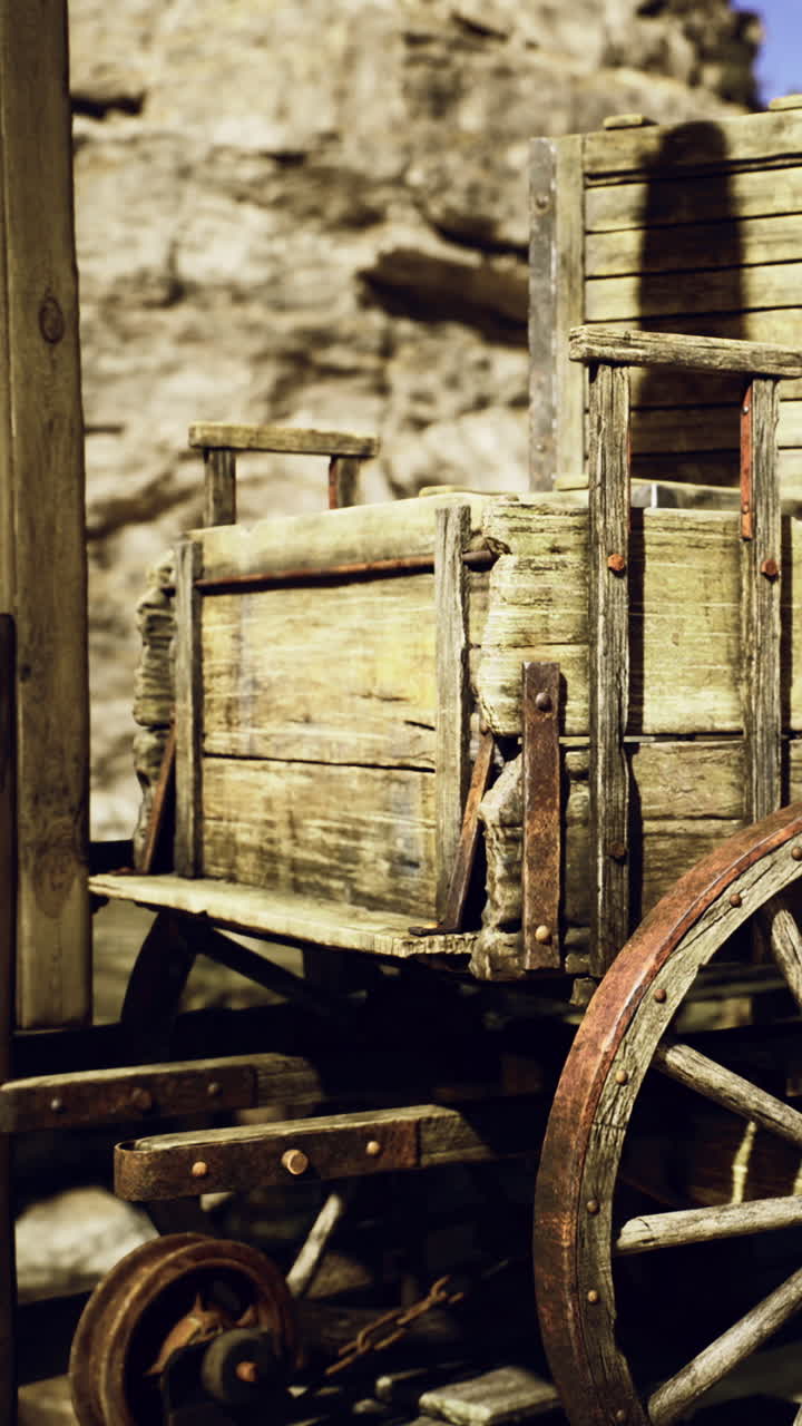 Carretto di legno rustico appoggiato a una formazione rocciosa accidentata sotto la calda luce del sole.