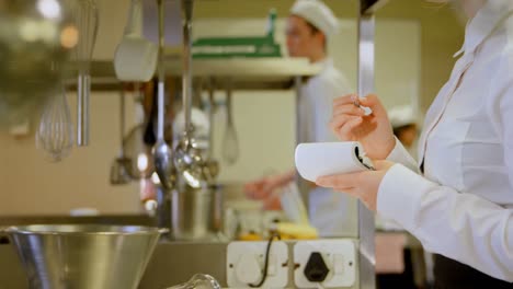 female chef writing on notepad in kitchen 4k