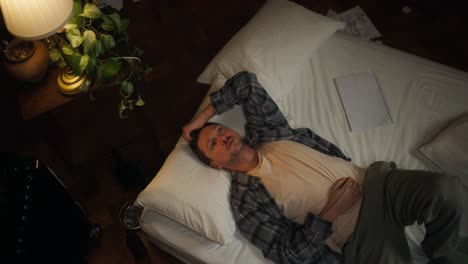 man lying on bed, depressed and thoughtful
