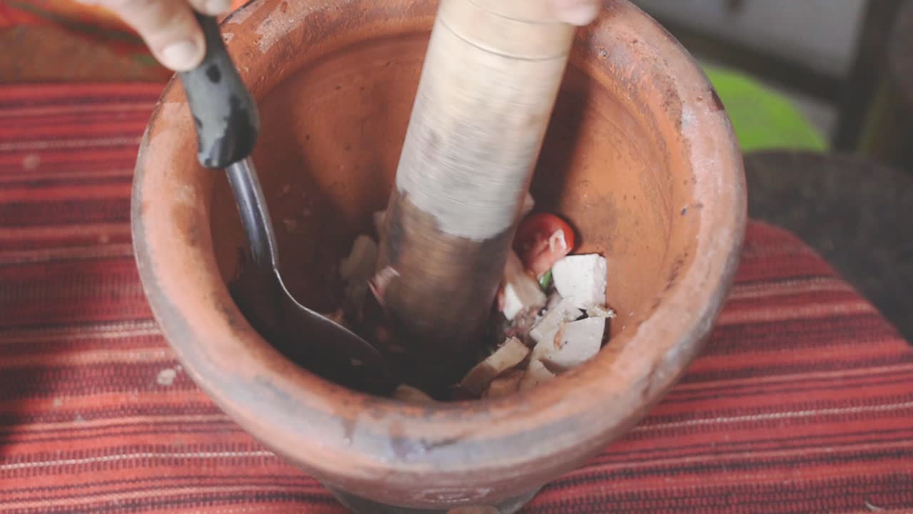 cocinando la serie som tam: la mano del vendedor de comida callejera en cámara lenta golpeando som tam o ingredientes de ensalada de papaya verde picante tailandesa con mortero en el puesto de comida callejera