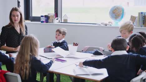 female teacher at a table with a group of schoolchildren in a primary school lesson, selective focus