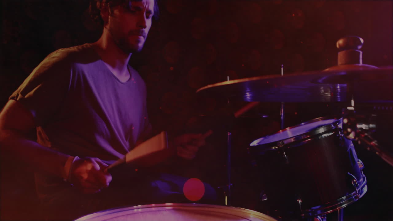 male drummer playing drum kit on dimly lit stage, showing animated sound waves for music production