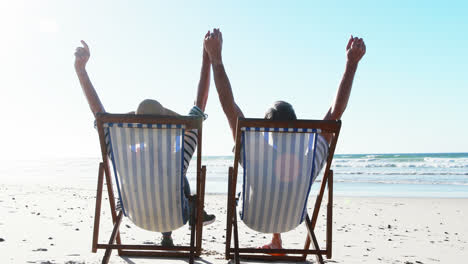 senior couple relaxing on sunlounger at beach