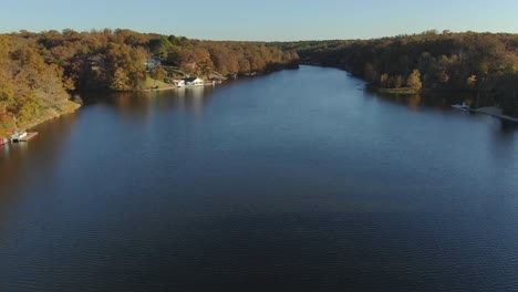 Unique-aerial-view-of-backward-ascent-and-then-descent-along-lake-shoreline-of-retirement-community-with-fall-colors-on-display