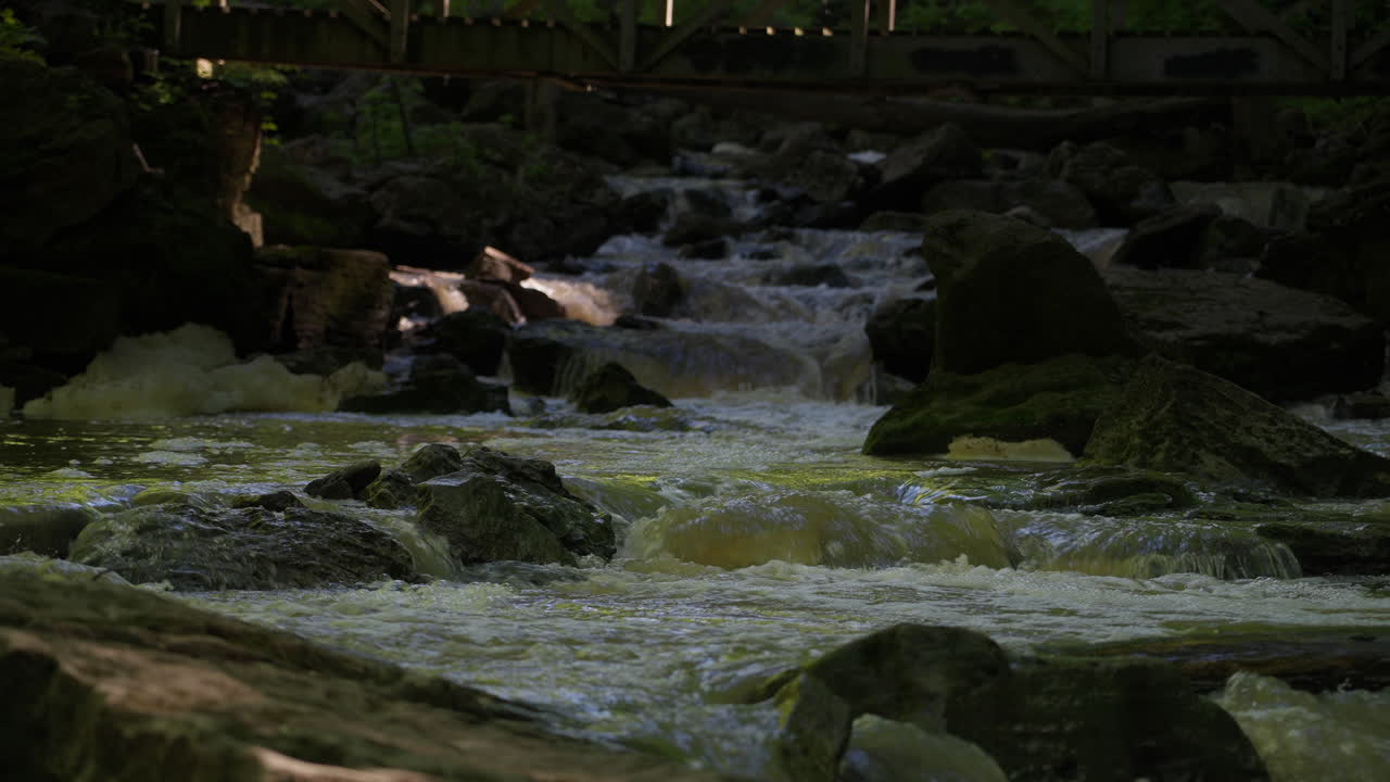 Calm flowing water over rocks beneath a wooden bridge at 15 Mile Creek, Niagara