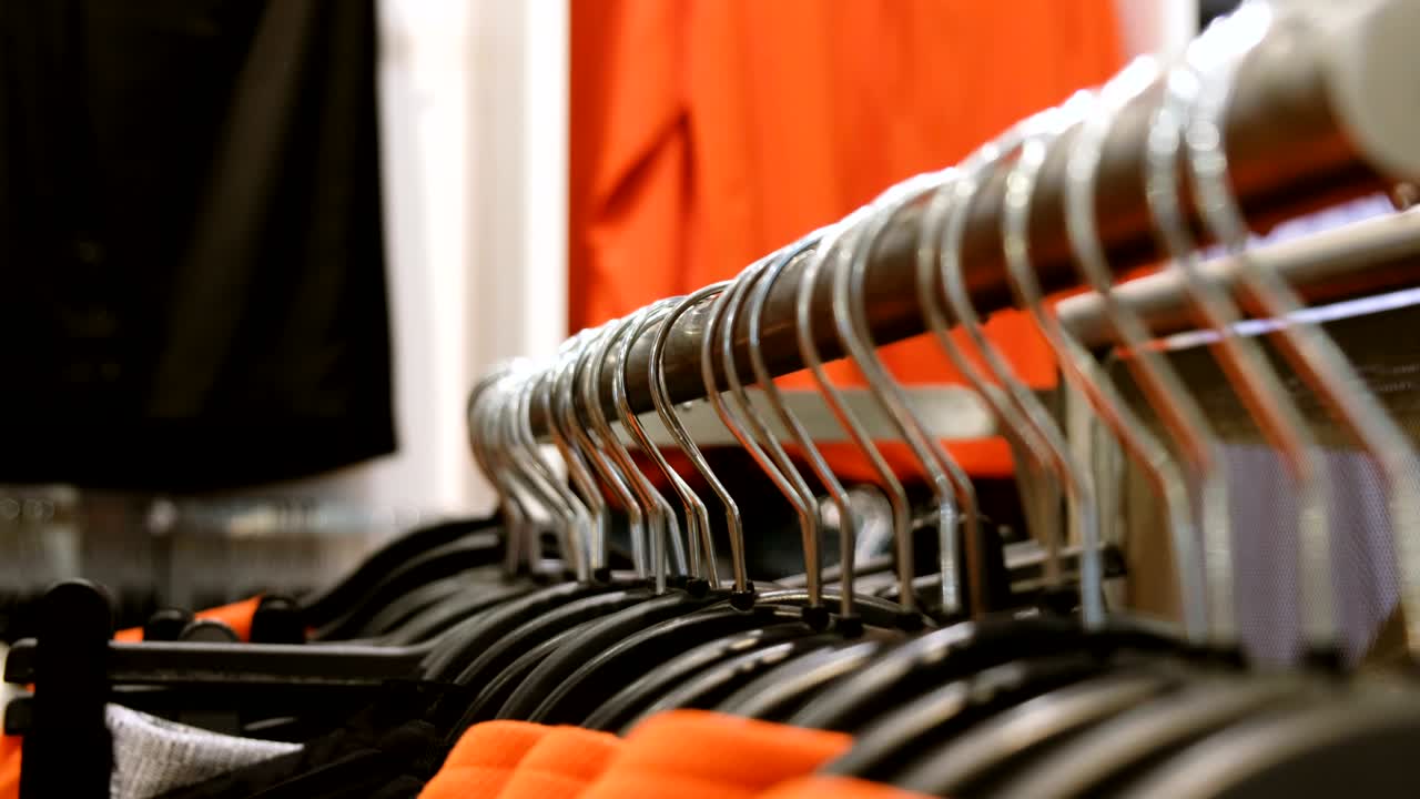 mujer devuelve ropa a un colgante en una tienda, primer plano