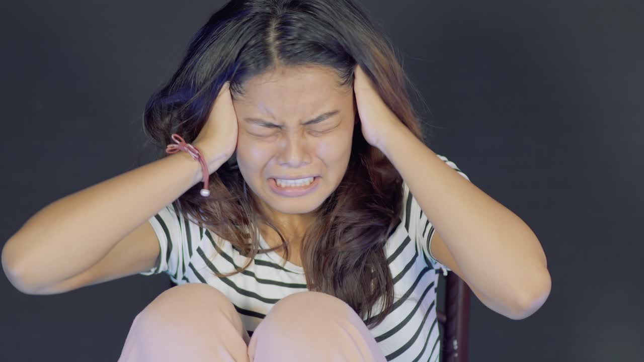 방에 혼자 앉아 비명을 지르는 젊은 두려운 아시아 소녀의 클로즈업