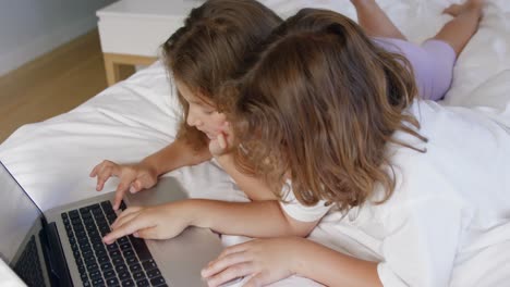 sibling using laptop on bed