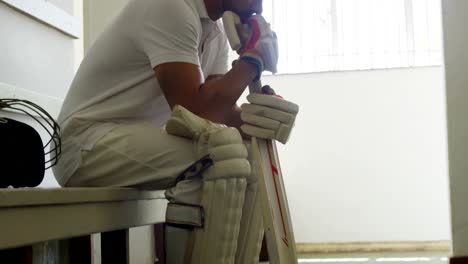 cricket player sitting on bench in dressing room