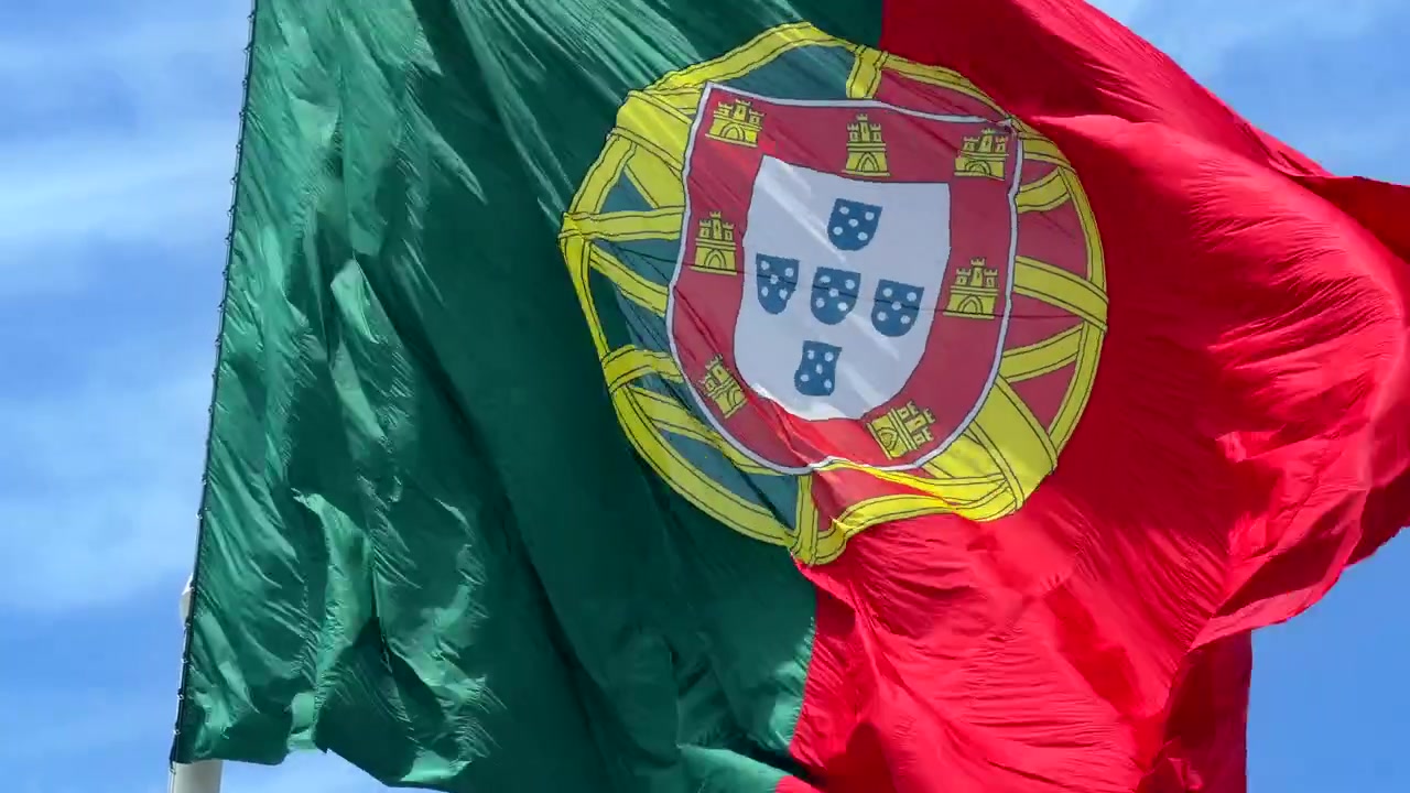 Bandera de Portugal ondeando contra un cielo azul claro
