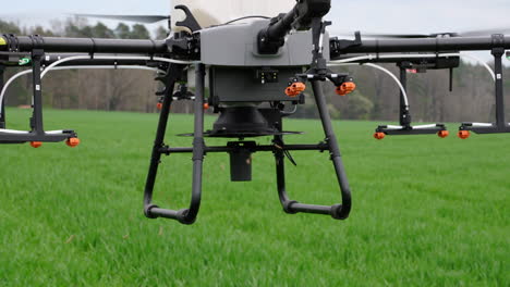 Drones-Agrícolas-Liberando-Fertilizante-En-Gránulos-Sobre-Tierras-Agrícolas-Verdes,-De-Cerca