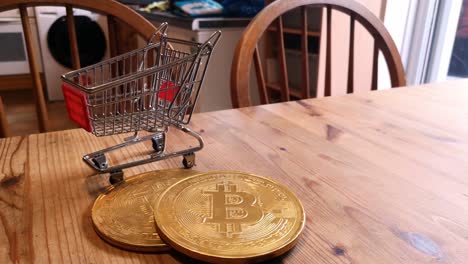 golden bitcoin crypto currency coins in tiny shopping trolley on kitchen table concept left rotating shot