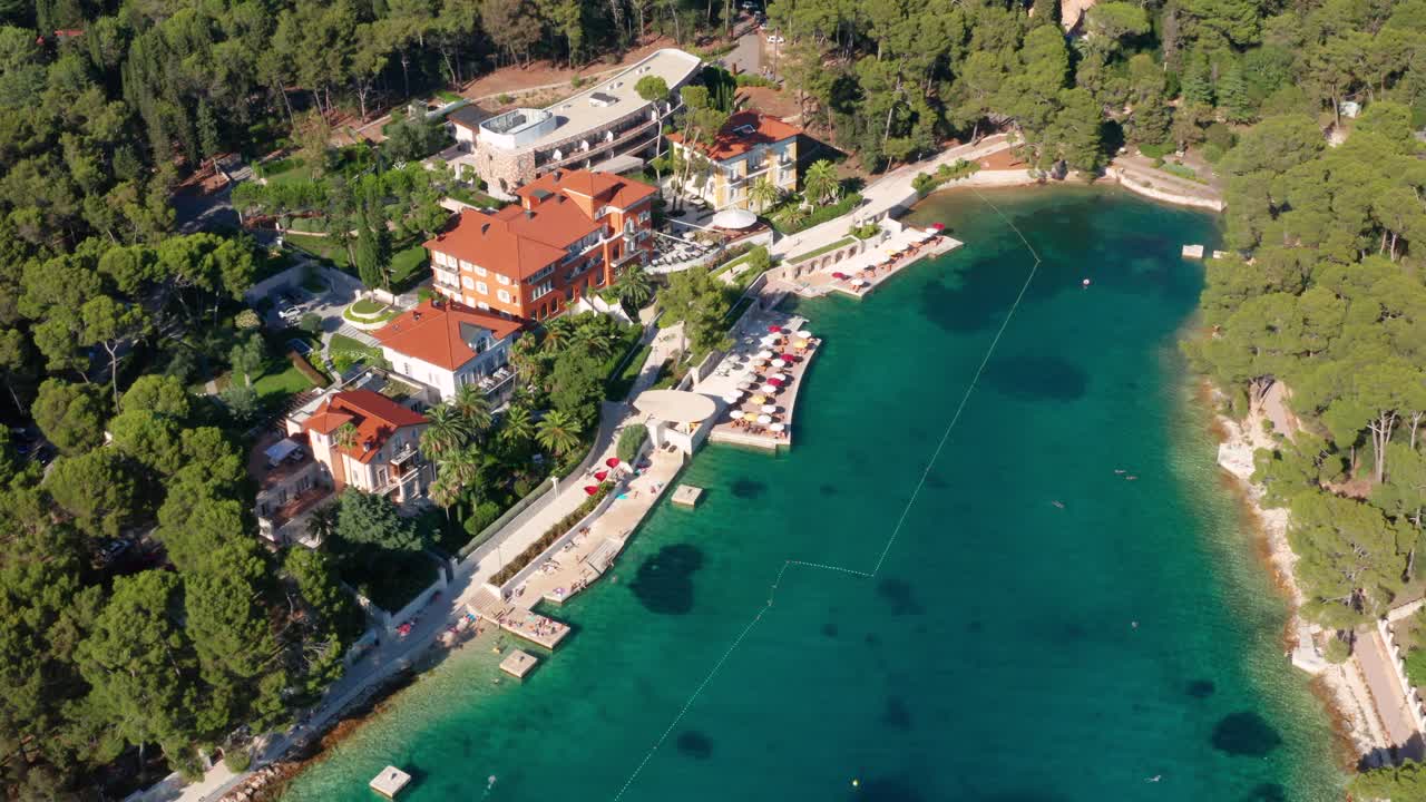 Letecký pohled na křišťálově čistou vodu malé zátoky vedle hotelu a mořského mola.