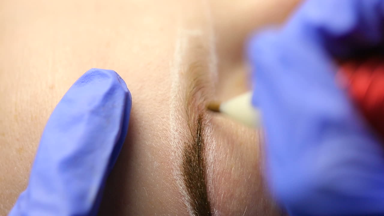 Woman in process of eyebrow tattoo. Close up of cosmetologist making permanent makeup