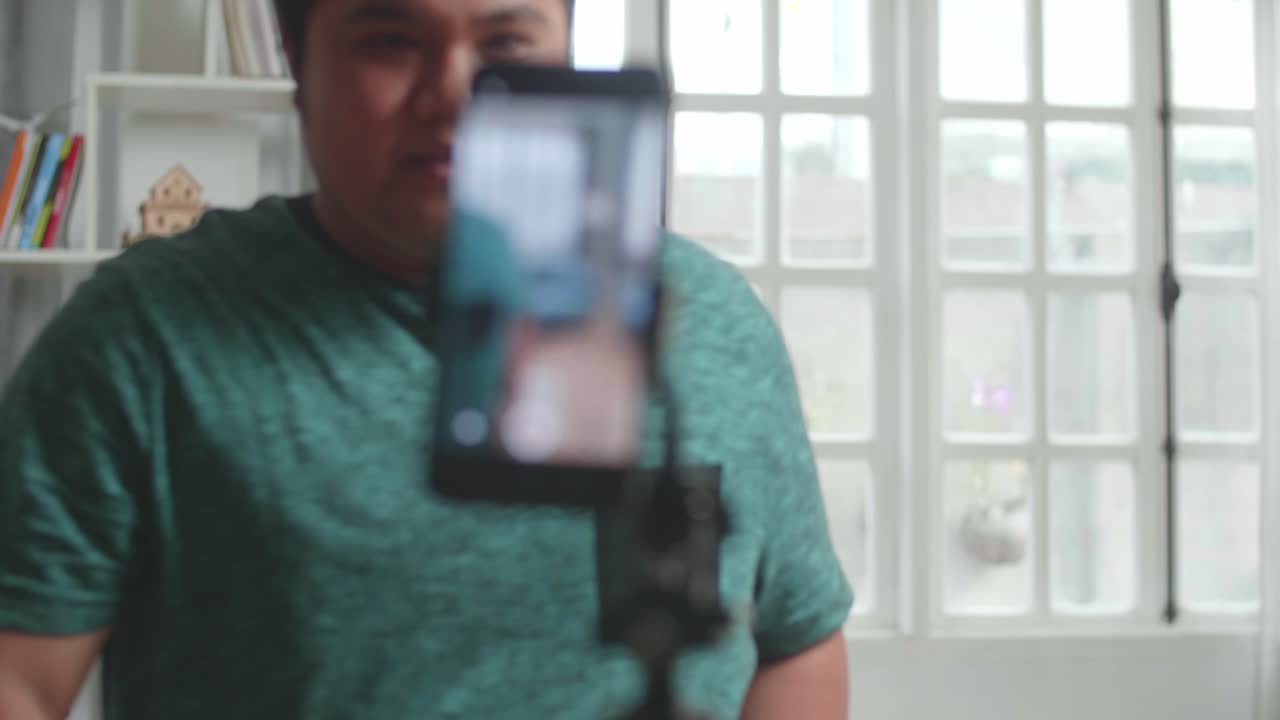 Blogger asiatico registra contenuti video per i social network con la fotocamera dello smartphone, mago con carte da gioco.