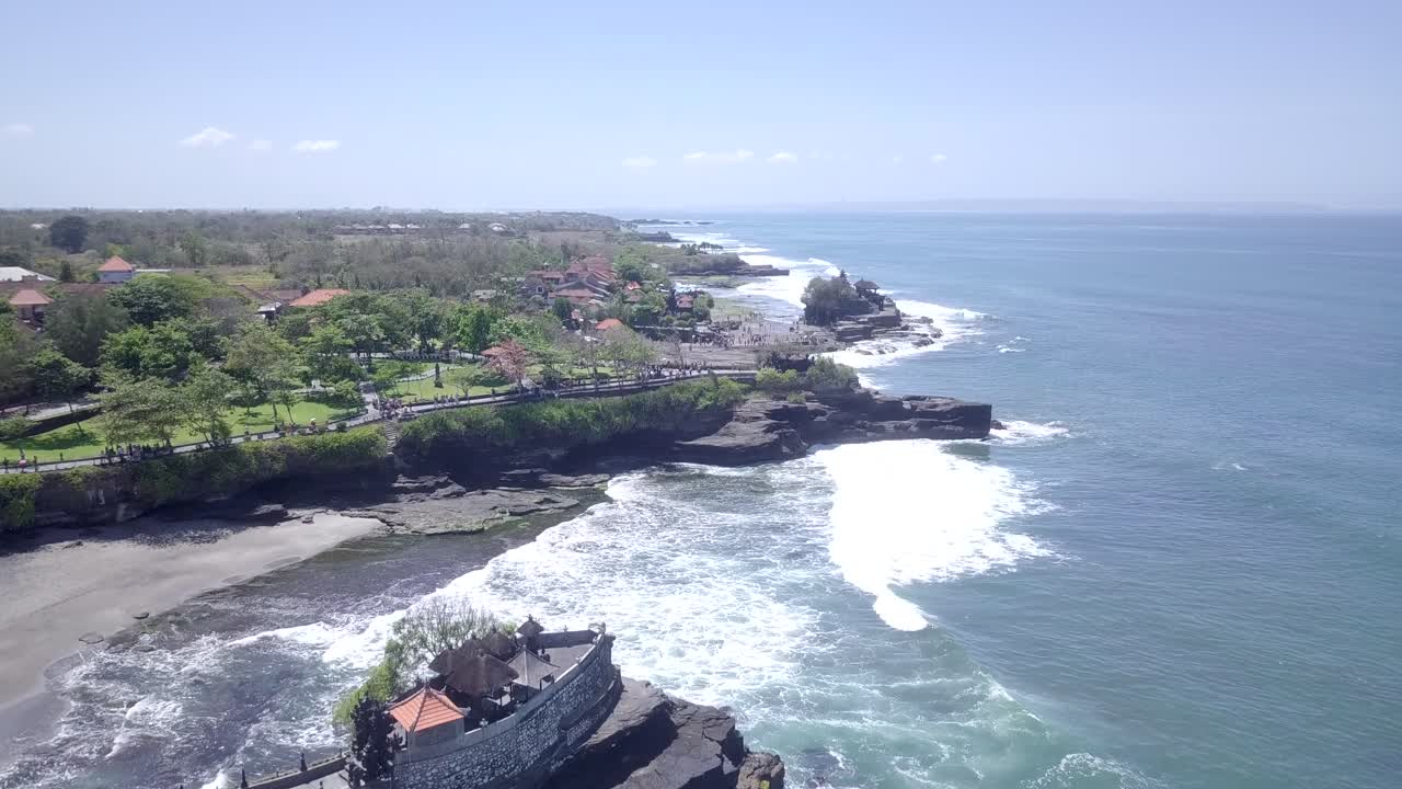 imagens de drone do templo tanah lot em um belo dia ensolarado nas praias turísticas do sul de bali, na indonésia.