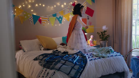 niña feliz saltando en la cama vistiendo disfraz jugando a un juego disfrutando de la imaginación juguetona en un dormitorio colorido en casa