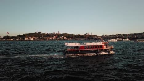 Static-view-of-ferry-boats-crossing-river-in-Bosphorus,-Turkey-in-the-evening-with-the-view-of-the-city-in-the-background