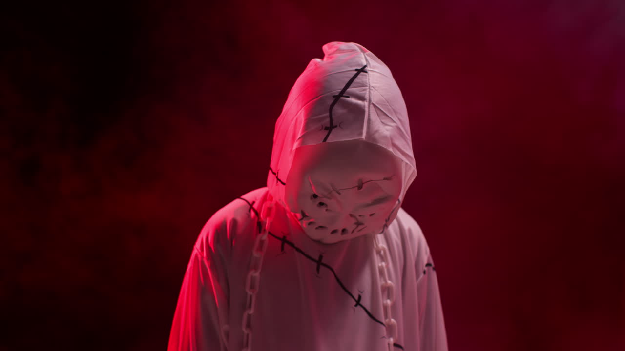 niño vestido de fantasma zombie monstruo disfraz truco o trato en halloween asustando a la gente contra el fondo de humo rojo 3