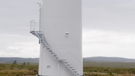 tilting shot of a wind farm turbine, its blades, the tower and the base