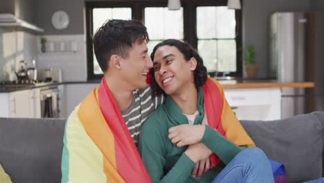 portrait of happy diverse male couple embracing with lgbt flag