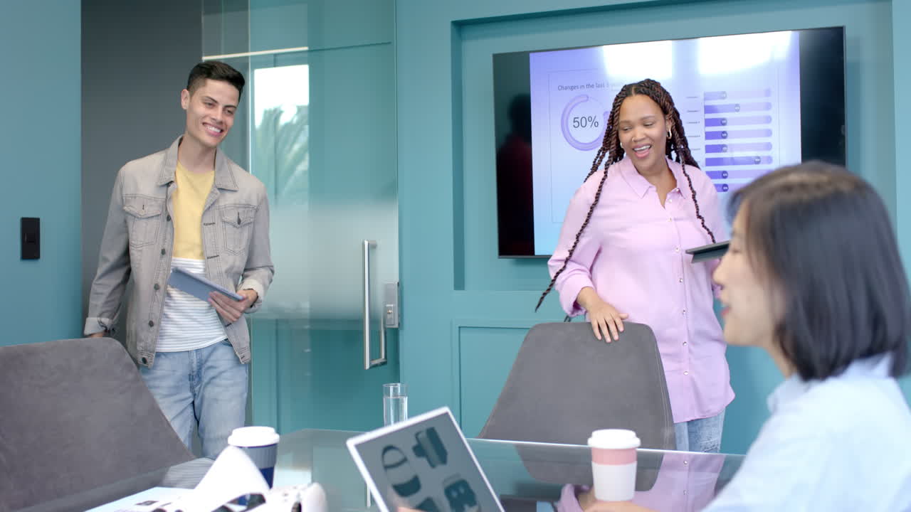 Collaborating in office, colleagues discussing presentation with tablet and laptop