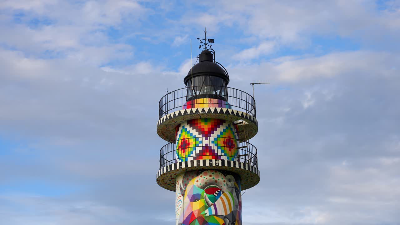 Ajo Lighthouse painted in vibrant geometric patterns by Okuda San Miguel under a cloudy sky