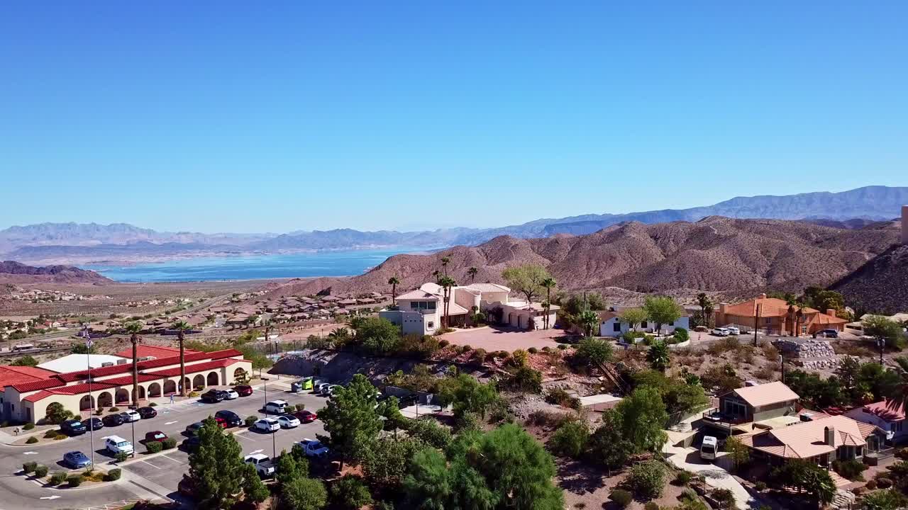 Drone above Boulder City Nevada tilting downward to reveal road in front of mountains and Lake Mead in the background