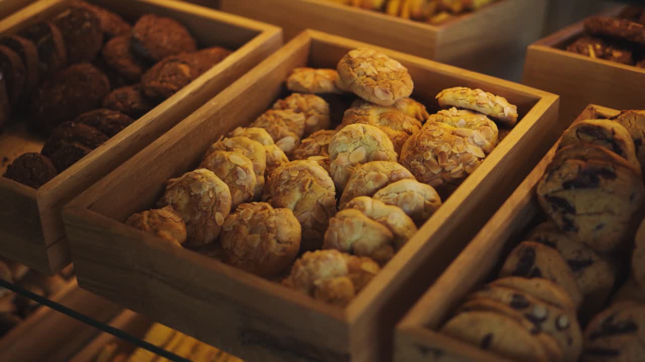 Assorterte kjeks i trekasser utstilt på varmt belyste bakeriglasshyller.