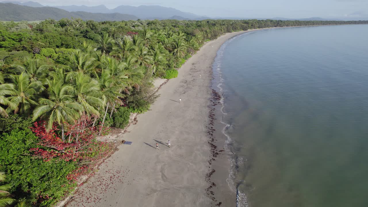 turistas caminando en la orilla arenosa de la playa de cuatro millas en port douglas, queensland, australia - toma aérea de drones