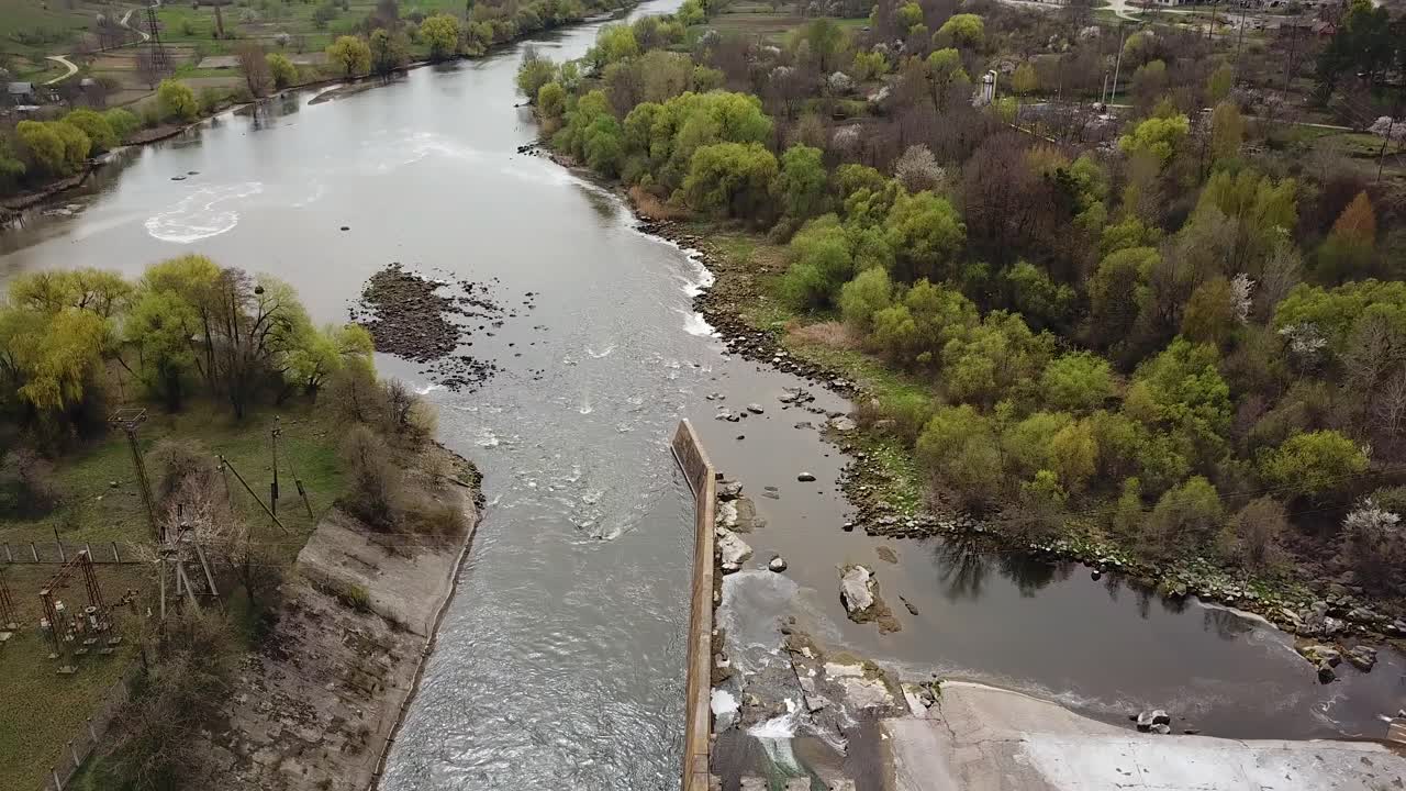 View of the two banks of the river and sewage treatment plant from a height in the summer. Landscape of suburban from the bird's eye view. Camera motion down. Aerial view.