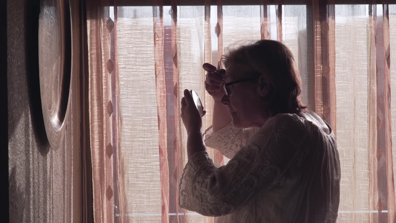 Senior Woman Applying Makeup by Window