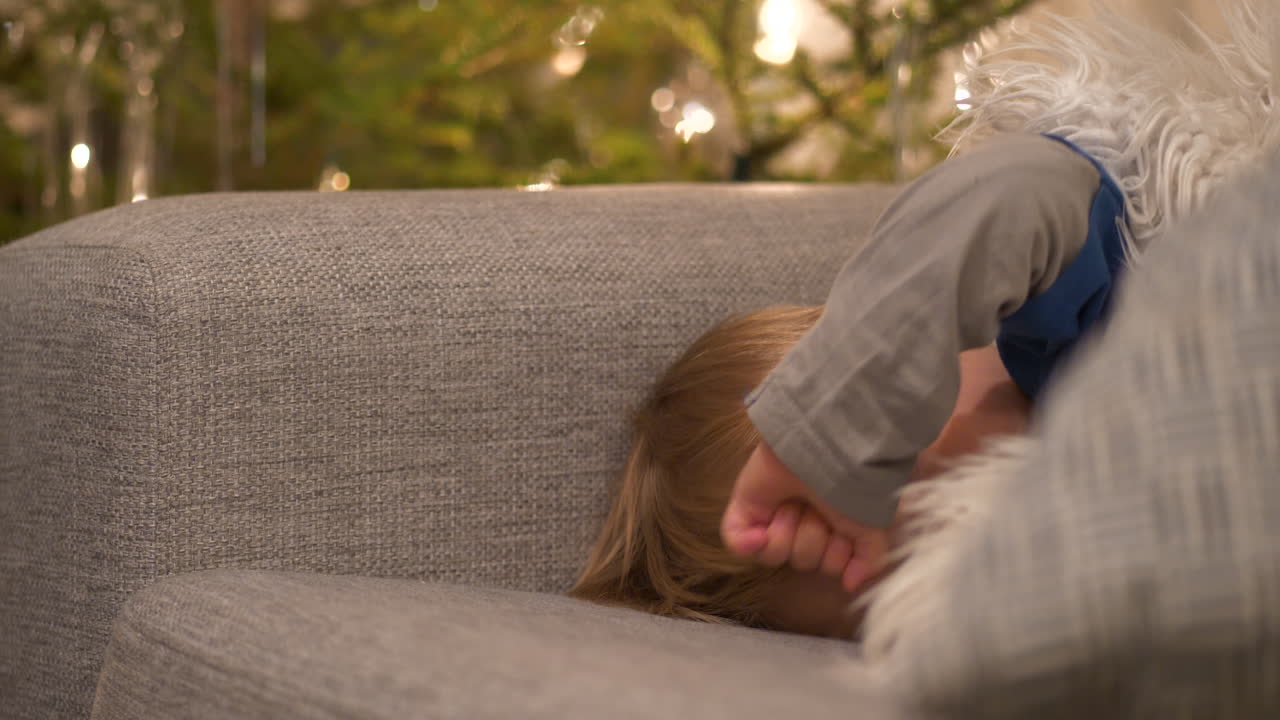 크리스마스 동안 소파에 누워 새로 깨어난 유아, 크리스마스 트리 배경, 클로즈업