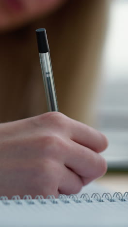 primer plano de la mano sosteniendo el bolígrafo sobre el cuaderno, listo para escribir, con la taza de café en la mesa de madera en borrón suave, captura el enfoque, la creatividad y la contemplación en un momento de escritura tranquilo